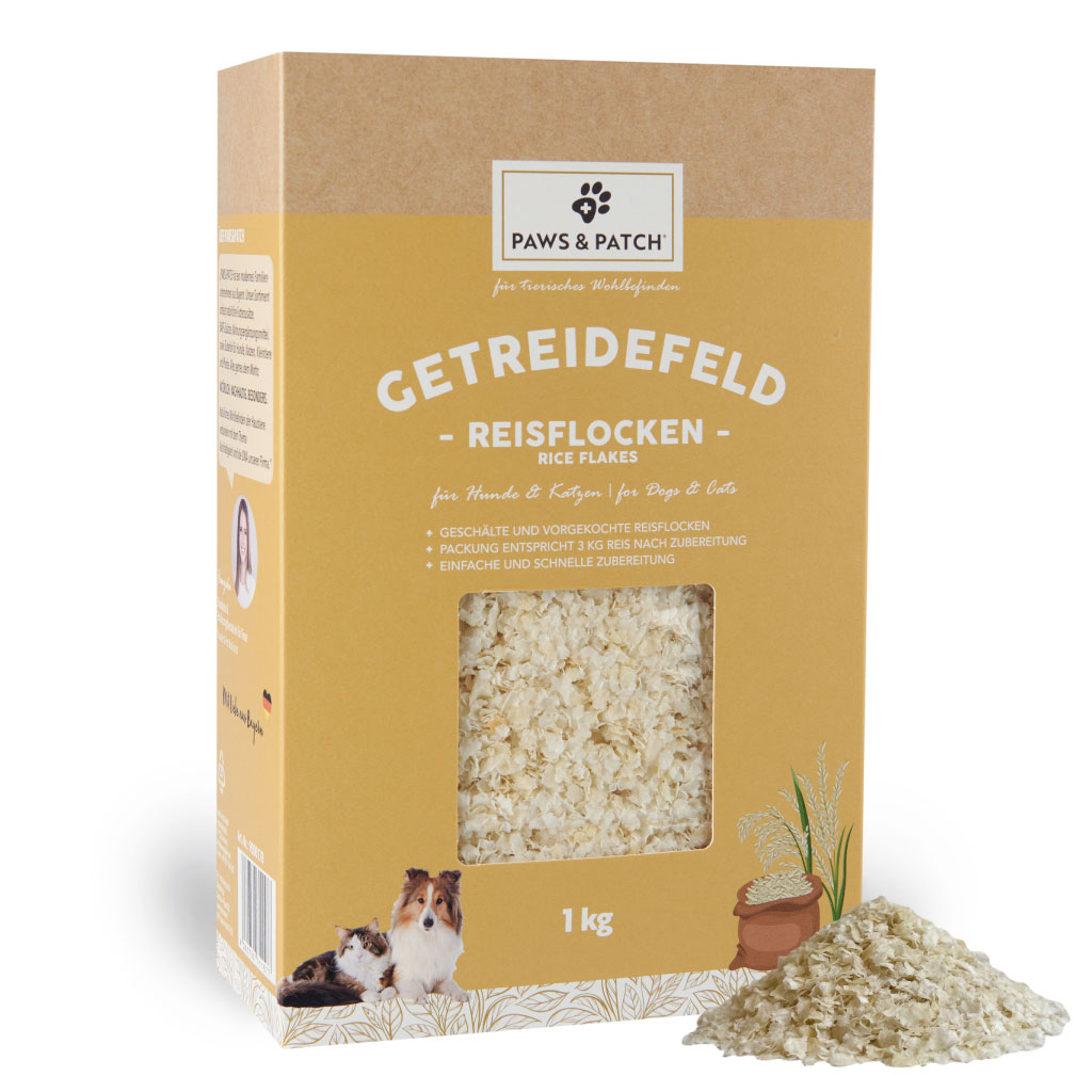 Beige Verpackung aus Pappe mit Sichtfenster, das Reisflocken zeigt - davor ein Häufchen ausgepackte Reisflocken